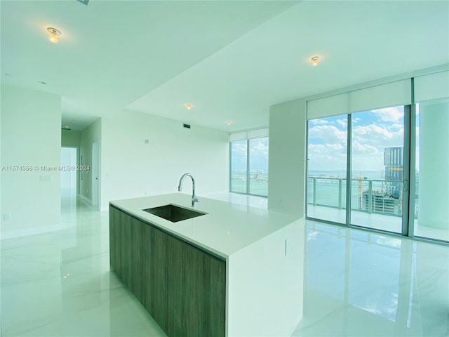 kitchen with a kitchen island, sink, floor to ceiling windows, and light tile flooring