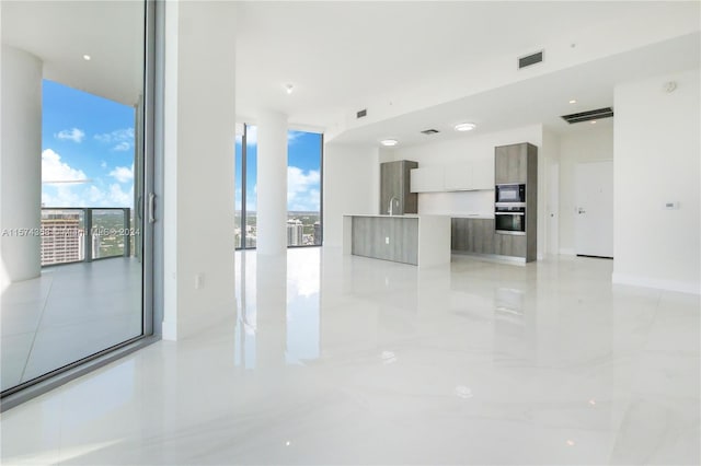 spare room featuring sink, expansive windows, and light tile floors