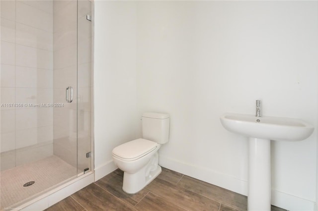 bathroom featuring a shower with door and toilet