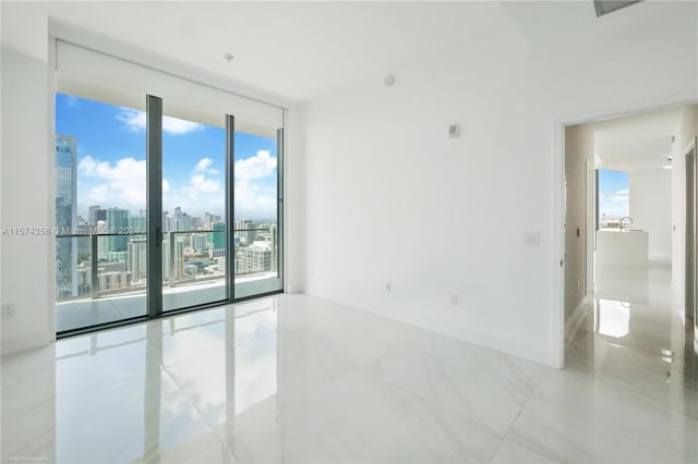 unfurnished room featuring a wealth of natural light, floor to ceiling windows, and tile floors