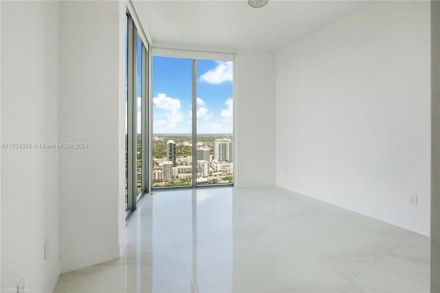 unfurnished room with concrete flooring and a wall of windows