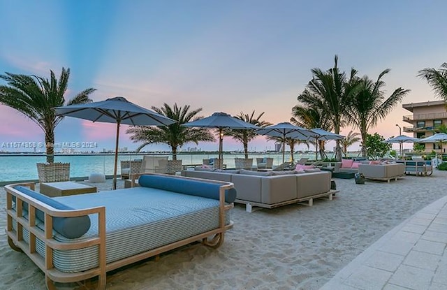 patio terrace at dusk featuring an outdoor living space and a water view