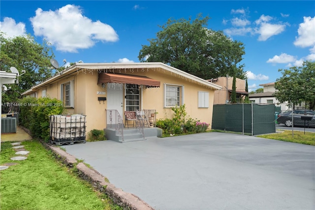 bungalow-style house featuring central air condition unit and a front lawn