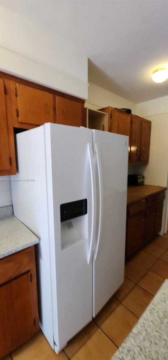 kitchen featuring white fridge with ice dispenser and light tile flooring