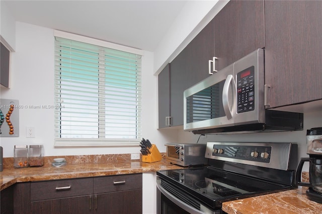 kitchen with light stone counters, black range with electric stovetop, and dark brown cabinetry