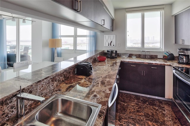 kitchen featuring dark brown cabinetry, light stone counters, sink, and stainless steel electric range