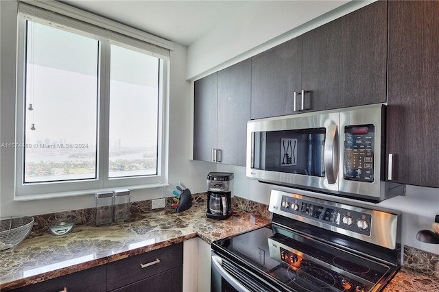 kitchen with appliances with stainless steel finishes, dark brown cabinetry, and stone countertops