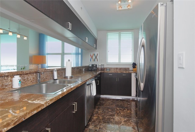 kitchen featuring appliances with stainless steel finishes, a wealth of natural light, stone counters, and sink