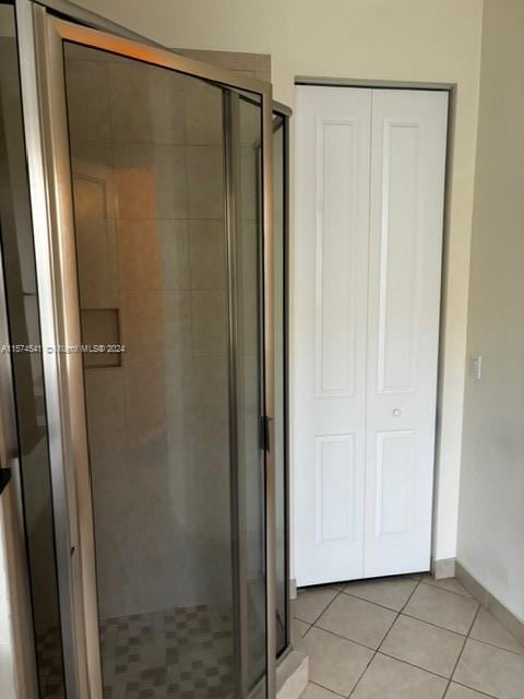 bathroom with a shower with door and tile flooring