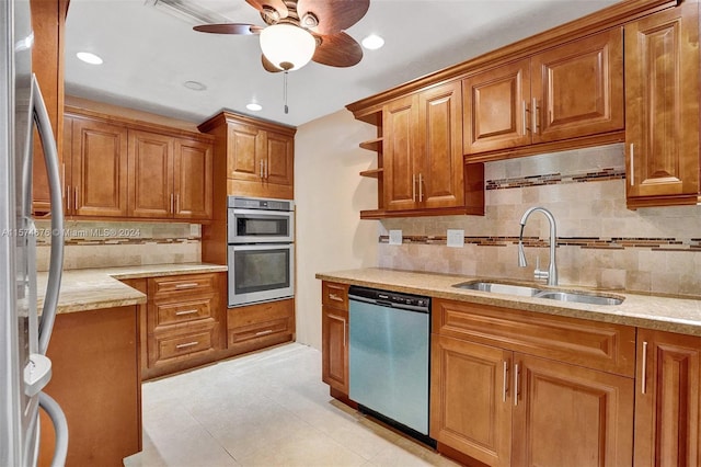 kitchen featuring backsplash, sink, ceiling fan, light stone countertops, and stainless steel appliances