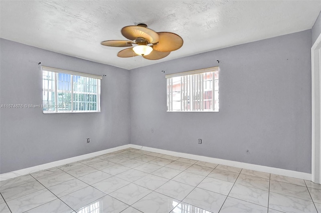 spare room featuring ceiling fan, plenty of natural light, and a textured ceiling