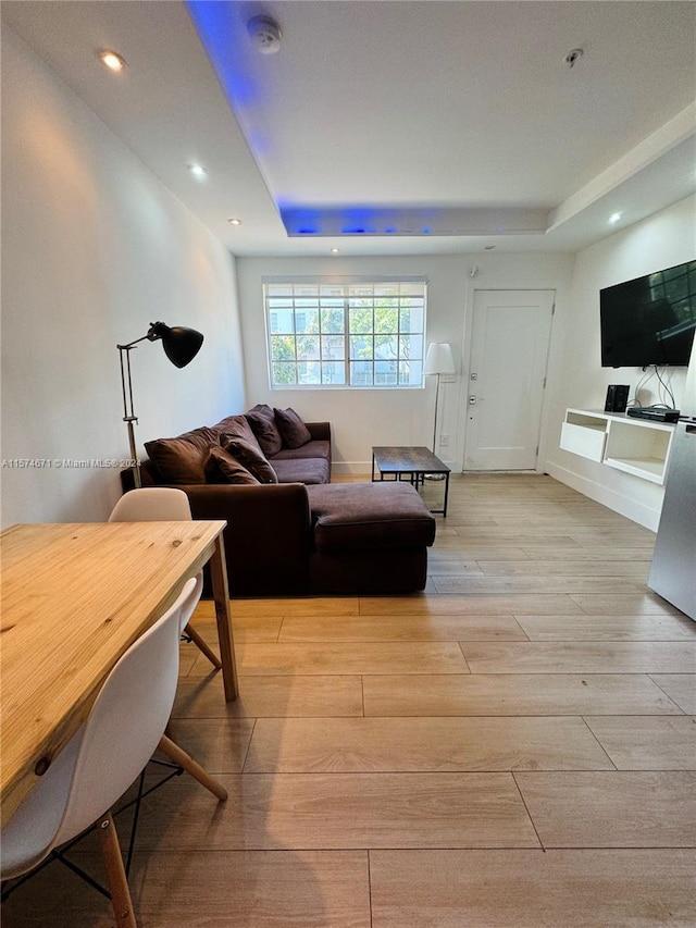 living room featuring light hardwood / wood-style floors and a raised ceiling