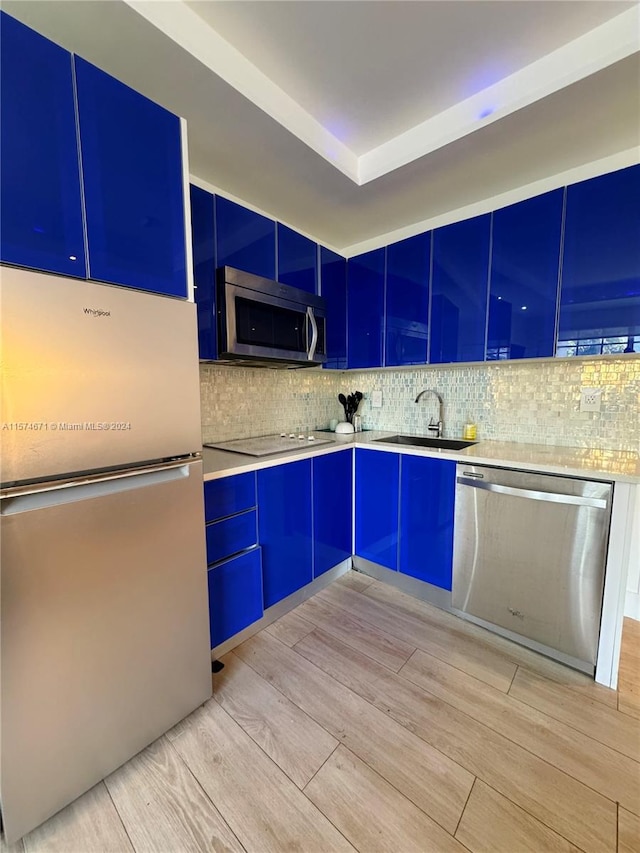 kitchen with backsplash, appliances with stainless steel finishes, sink, light hardwood / wood-style floors, and blue cabinets