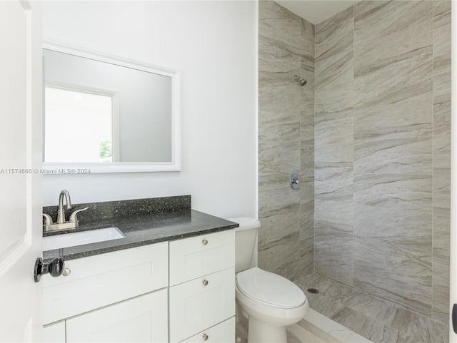 bathroom with vanity, a tile shower, and toilet