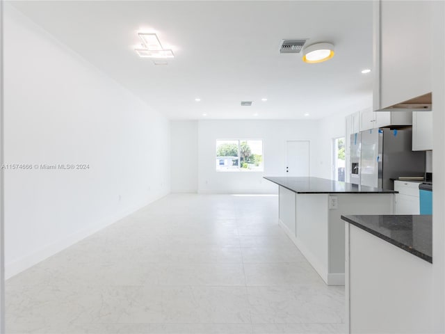 kitchen with stainless steel refrigerator with ice dispenser, a center island, and white cabinetry