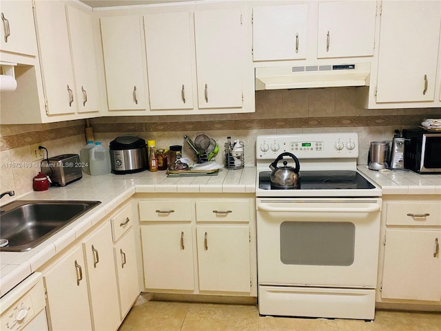 kitchen with backsplash, tile counters, custom exhaust hood, sink, and white appliances