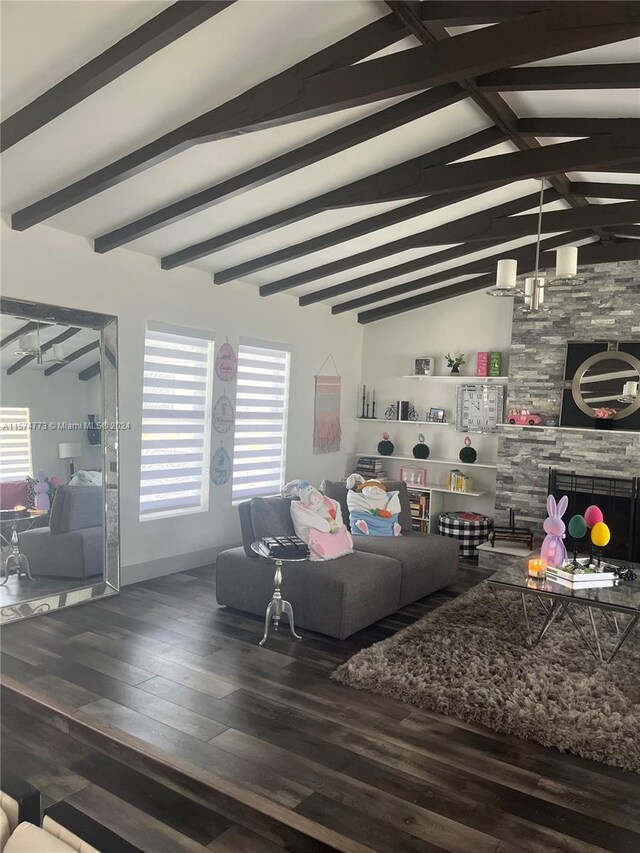 living room featuring vaulted ceiling with beams, hardwood / wood-style flooring, and a stone fireplace