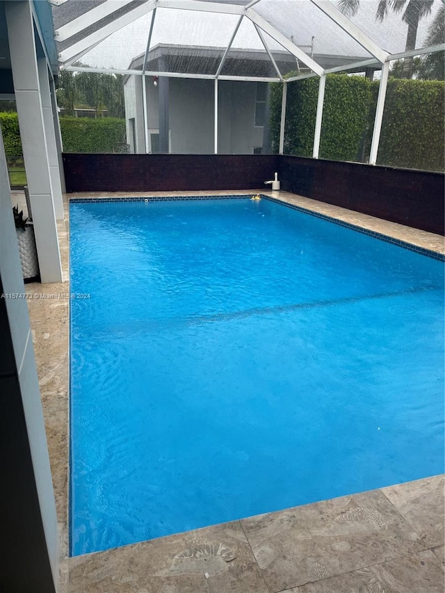 view of swimming pool featuring a lanai