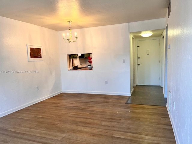 empty room featuring a notable chandelier and dark hardwood / wood-style floors