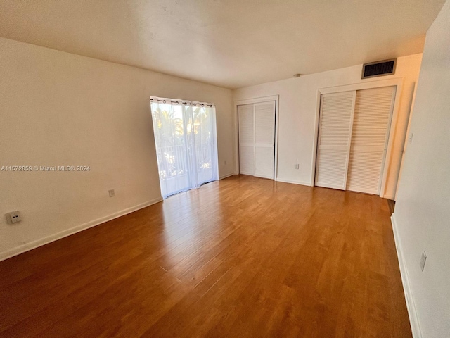 unfurnished bedroom featuring multiple closets and hardwood / wood-style flooring