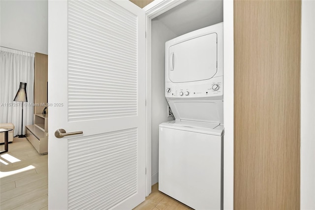 laundry area featuring stacked washing maching and dryer, laundry area, and light wood finished floors