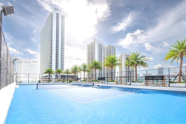 view of tennis court featuring a view of city and fence