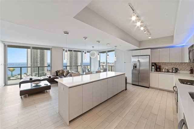 kitchen featuring decorative light fixtures, appliances with stainless steel finishes, backsplash, track lighting, and a chandelier