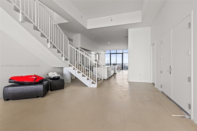 playroom featuring concrete flooring, a towering ceiling, expansive windows, and a water view