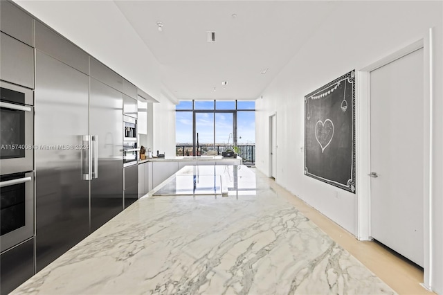 kitchen with appliances with stainless steel finishes, gray cabinets, and light stone counters