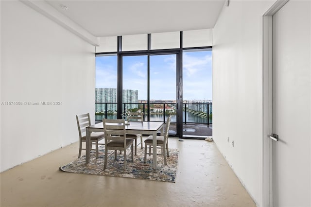 dining room featuring a healthy amount of sunlight, concrete floors, expansive windows, and a water view