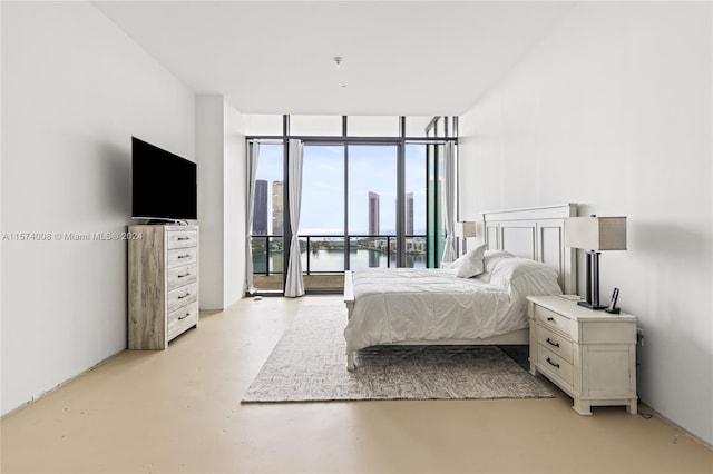 bedroom featuring expansive windows, access to outside, and a water view