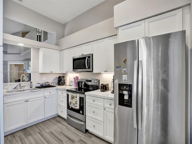 kitchen featuring light stone countertops, white cabinets, and stainless steel appliances