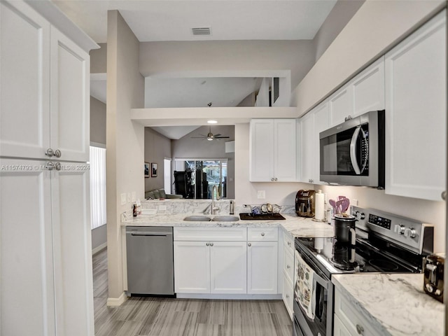 kitchen featuring stainless steel appliances, white cabinets, ceiling fan, and light stone counters