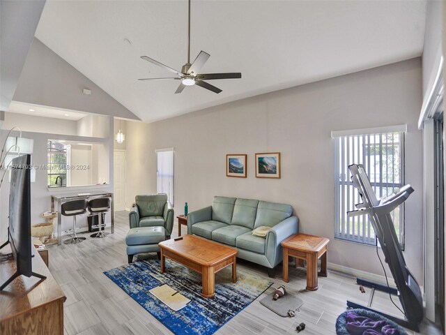 living room with high vaulted ceiling, light hardwood / wood-style floors, ceiling fan, and a healthy amount of sunlight