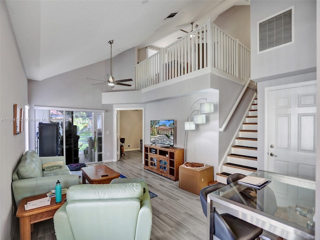 living room featuring high vaulted ceiling, ceiling fan, and light wood-type flooring