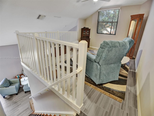 staircase with hardwood / wood-style flooring, ceiling fan, and vaulted ceiling