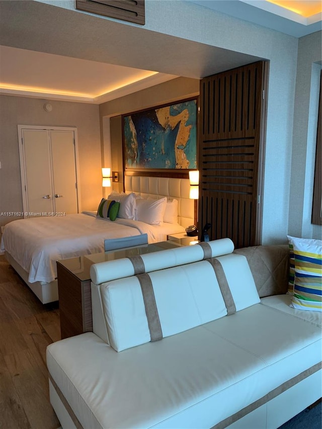 bedroom with dark wood-type flooring and a tray ceiling