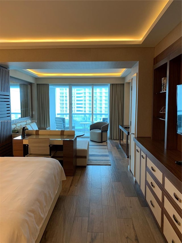 bedroom featuring multiple windows, a raised ceiling, and hardwood / wood-style flooring