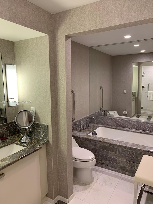 bathroom featuring tile flooring, tiled tub, vanity, and toilet