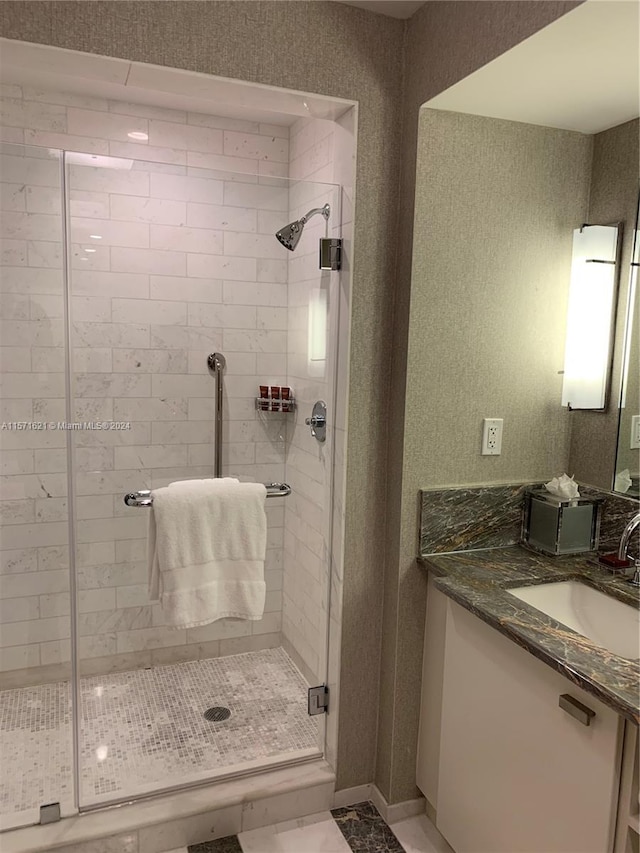 bathroom with a shower with shower door, tile floors, and vanity