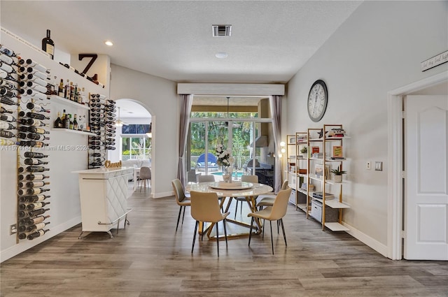 dining space featuring wood-type flooring and a textured ceiling