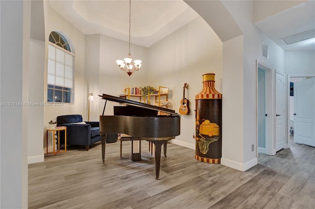 misc room featuring wood-type flooring, a towering ceiling, and a chandelier