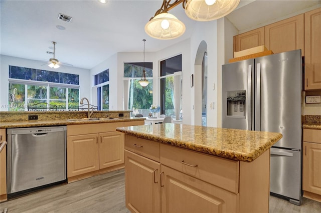 kitchen with pendant lighting, stainless steel appliances, light wood-type flooring, ceiling fan, and sink