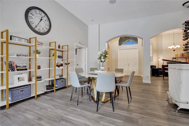 dining space with an inviting chandelier, high vaulted ceiling, and hardwood / wood-style floors