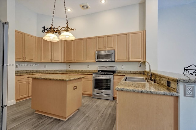 kitchen featuring sink, kitchen peninsula, appliances with stainless steel finishes, a center island, and a towering ceiling