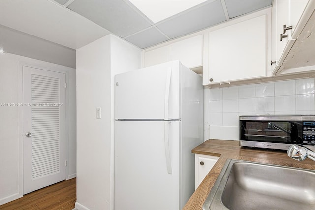 kitchen featuring white fridge, white cabinets, sink, backsplash, and hardwood / wood-style floors