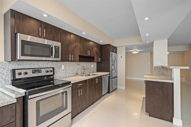 kitchen with light stone countertops, stainless steel appliances, backsplash, and sink