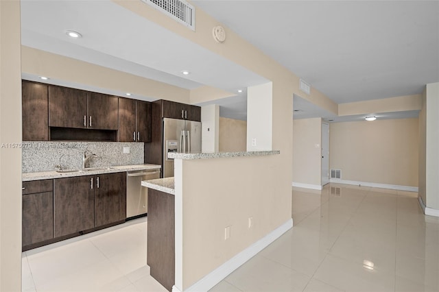 kitchen with stainless steel appliances, tasteful backsplash, visible vents, a sink, and dark brown cabinetry