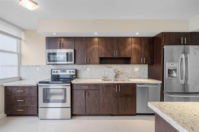 kitchen with dark brown cabinets, appliances with stainless steel finishes, a sink, and decorative backsplash