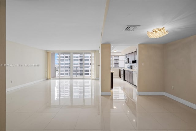 unfurnished room with light tile patterned floors, baseboards, floor to ceiling windows, and visible vents